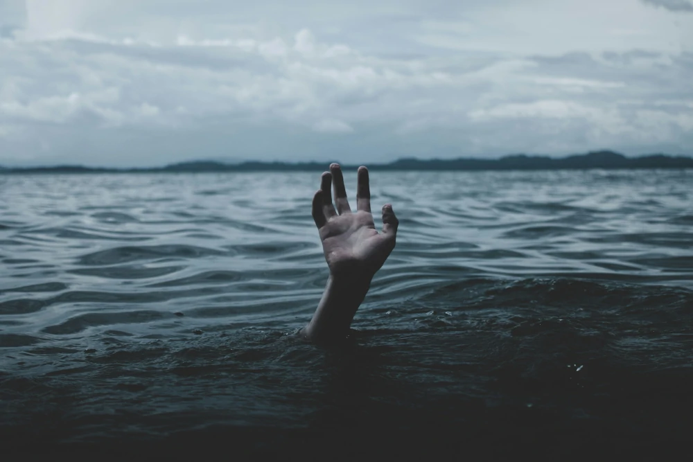 Bild einer Hand, die aus dem Wasser raus schaut, ohne dass man den Rest des Körpers sieht.